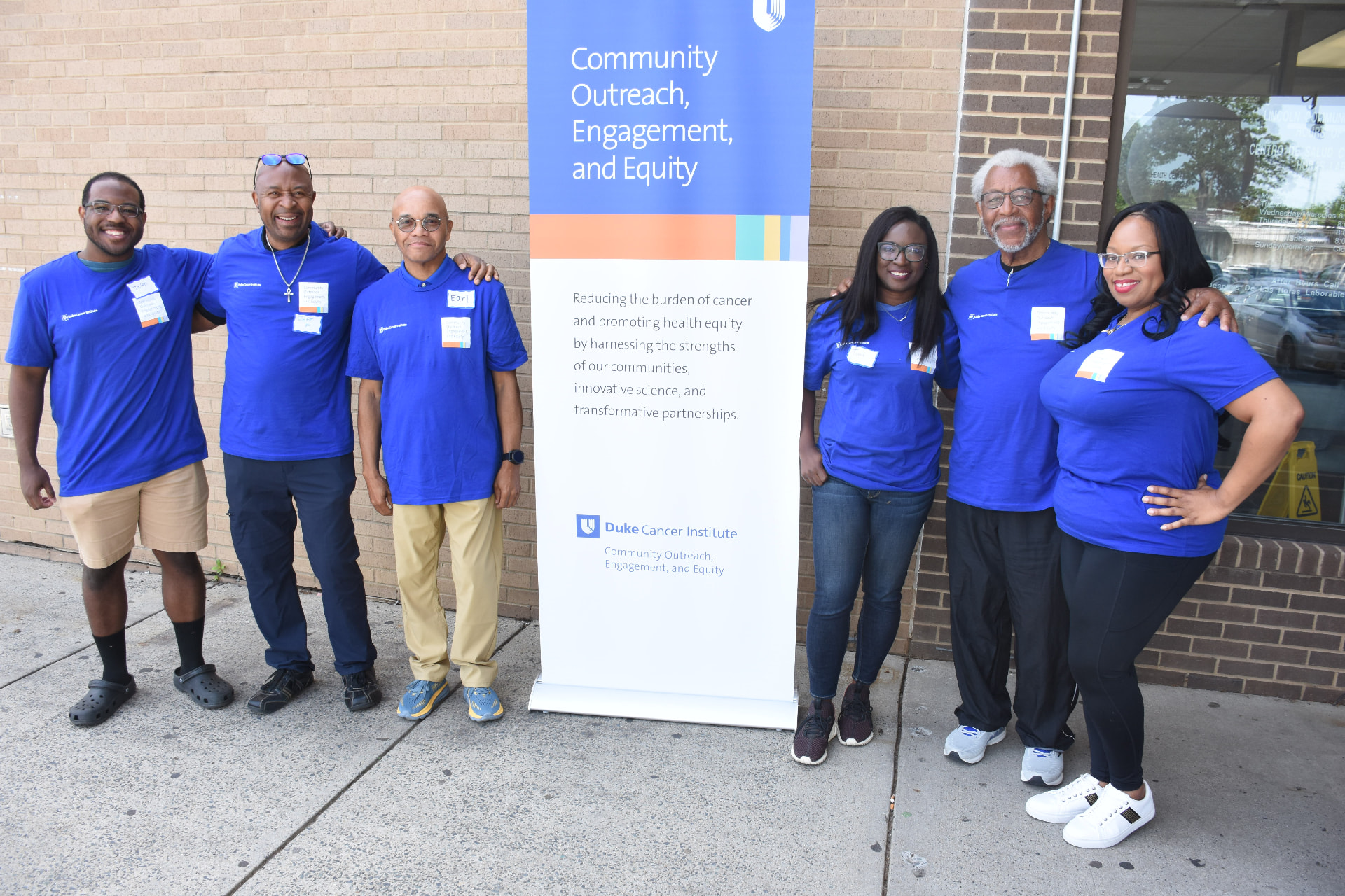 REGAL and Duke Cancer Institute Community Outreach, Engagement and Equity team standing beside a program banner outside a community health center