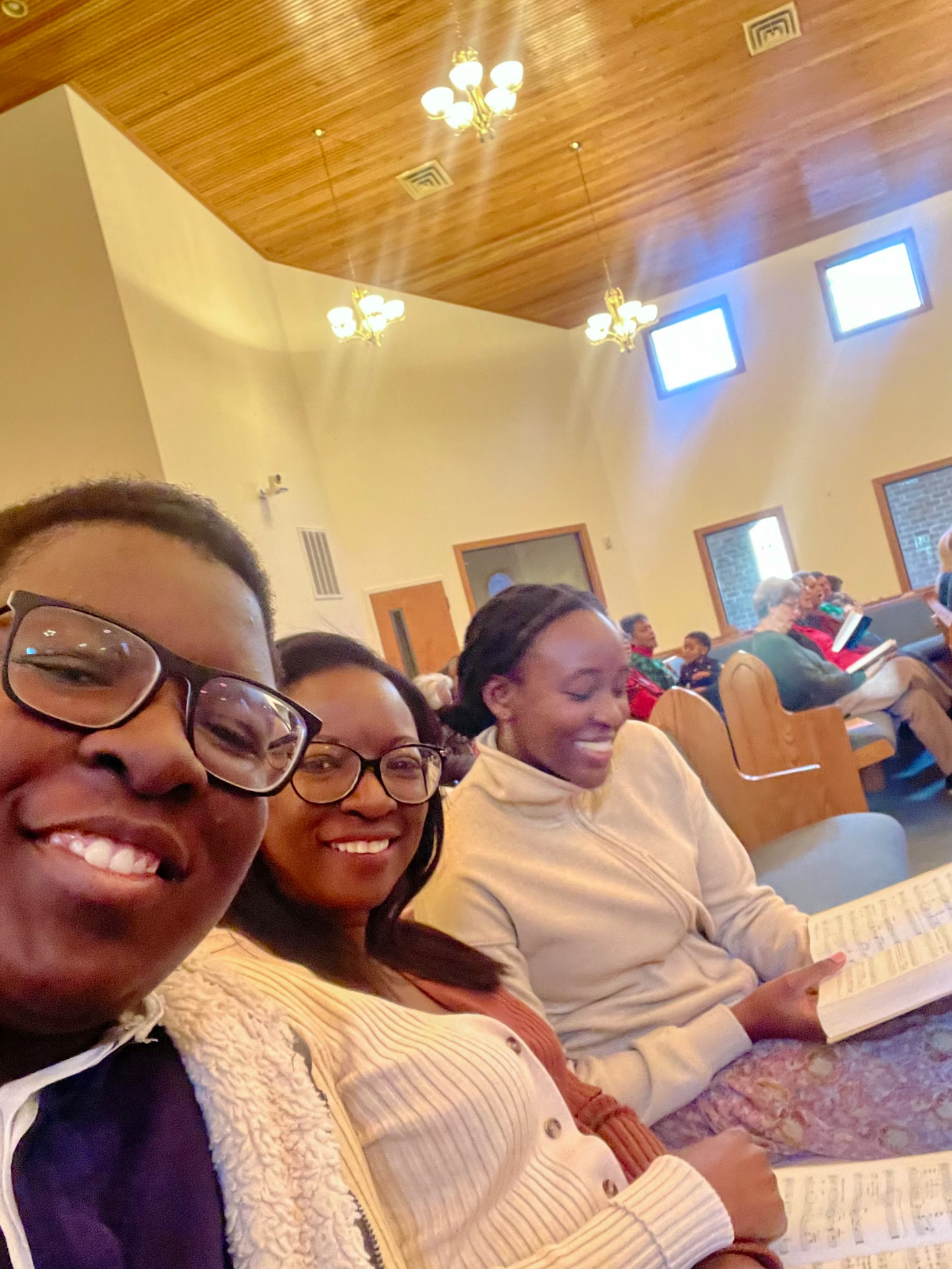 Three team members smiling during a community outreach visit at a local church